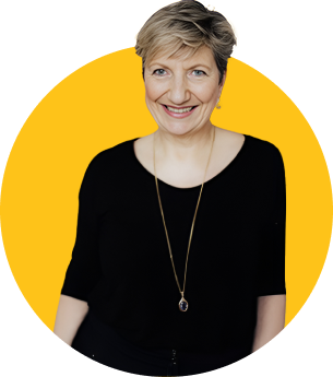 Das Bild zeigt die ZamStarten Trainerin und Gründerin des Gründerzentrums Gaby Köhler. Gaby hat kurze, blond gefärbte Haare und trägt ein schwarzes, lockeres Oberteil mit einer Kette. Sie lächelt in die Kamera.