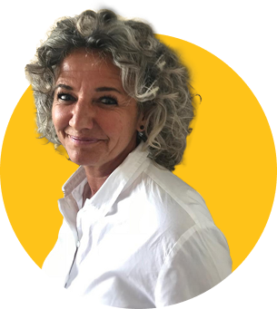 Das Bild zeigt die ZamStarten Trainerin Silke Lechner. Sie hat dunkelgraue, kurze lockige Haare und trägt eine weiße Bluse. Sie lächelt in die Kamera.